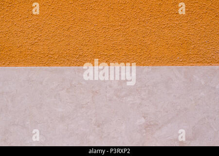 Two colours wall background. Orange painted and beige marble wall Stock Photo