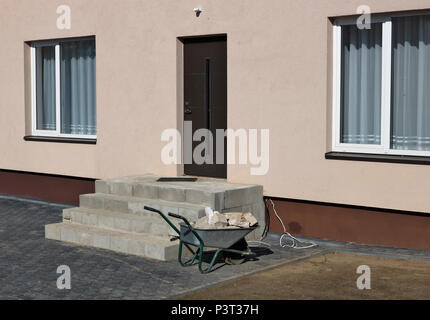 A wheelbarrow with stones near a rural house under construction.Sunny summer day shot Stock Photo