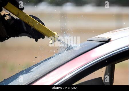 A 144th Civil Engineer Squadron firefighter cuts through a windshield during a training exercise at the Fresno Air National Guard Base July 10, 2016. The 144th CES firefighters also had the opportunity to train using hydraulic rescue tools, also known as Hurst's Jaws of Life, during the exercise. (U.S. Air National Guard photo by Senior Airman Klynne Serrano) Stock Photo