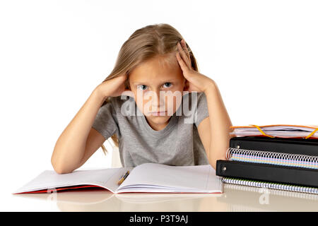 sweet young little schoolgirl pulling her hair desperate in stress while sitting on school desk doing homework tired and exhausted screaming crazy iso Stock Photo