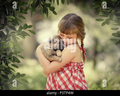 Little girl with Little cute girl with closed eyes gently hugs a little puppya puppy Stock Photo