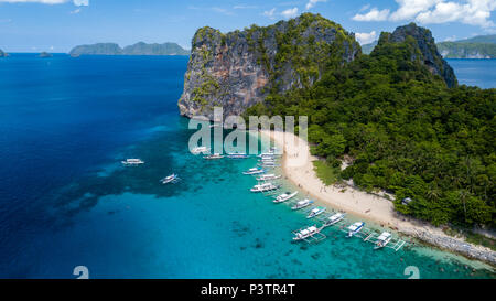 Aerial drone view of a beautiful tropical beach and island surrounded by coral reef and traditional Banca boats Stock Photo