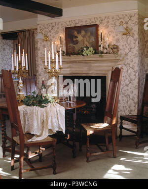 Antique chairs and table in Victorian style dining room with patterned wallpaper Stock Photo