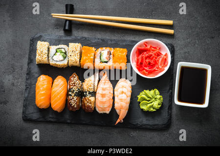 Sushi and sushi roll set on black stone table top view. Traditional asian food. Stock Photo