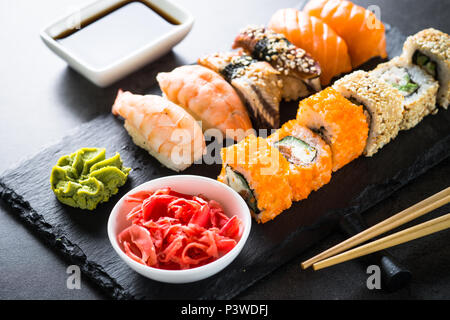 Sushi and sushi roll set on black stone table. Traditional asian food. Stock Photo