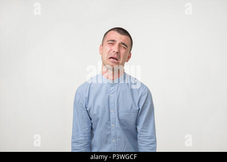 Studio shot of young handsome man, pouting and crying, complaining about girlfriend. Concept of being offended or breaking with wife. Failure in work  Stock Photo