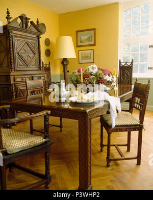 Pewter coffee pot on dark wood table with matching chairs in French country dining room with parquet flooring Stock Photo