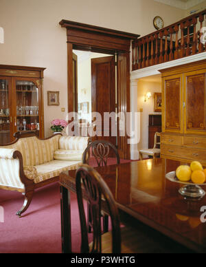 Antique French sofa and mahogany table and chairs in country dining room Stock Photo