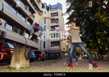 Three friends is having fun while one guy is jumping from wall Stock Photo