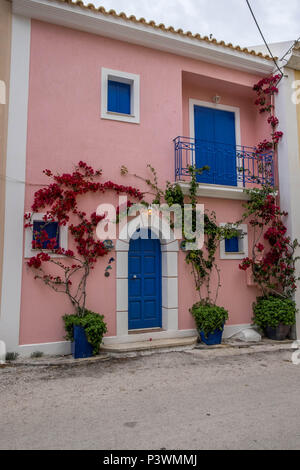 Pink painted house with red flowers growing up and around the door. Stock Photo