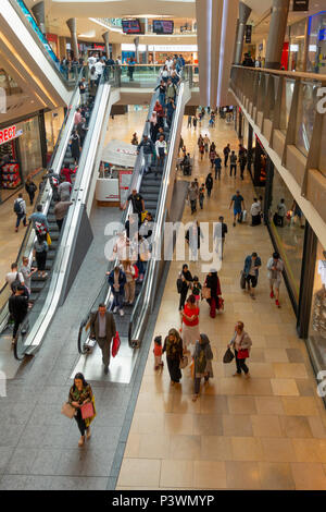 Shoppers on and around escalators in the Bullring shopping centre; Birmingham City Centre, England, UK. Motion blur on some people. Stock Photo