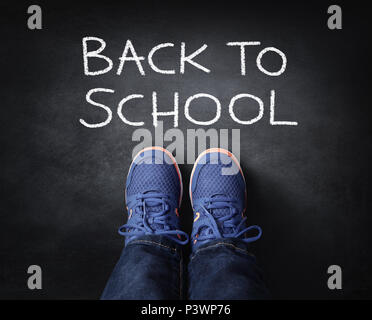 Back to school child in sneakers standing next to chalk writing on blackboard Stock Photo