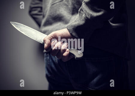 Criminal with knife weapon hidden behind his back Stock Photo