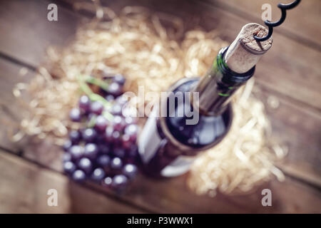 Bottle of wine, grapes, cork and corkscrew on wooden table Stock Photo