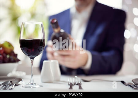Businessman reading red wine bottle label in restaurant concept for business lunch or dinner meeting Stock Photo