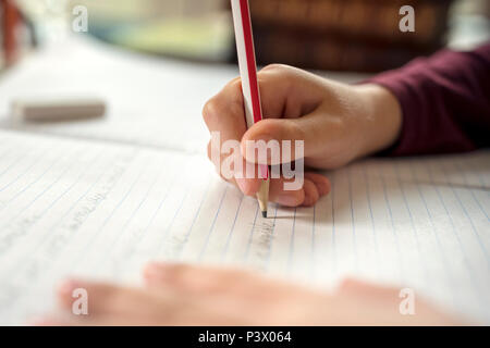 Boy writing in a notepad doing his school work spelling or homework Stock Photo