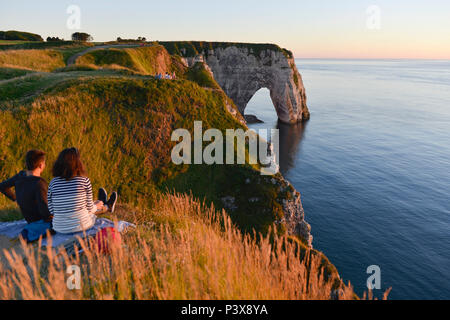 Etretat (northern France), town along the 'Cote d'Albatre' (Norman coast), in the area called 'pays de Caux'. Couple seated at nightfall, looking at t Stock Photo