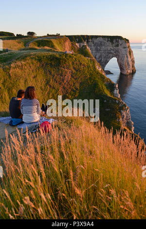 Etretat (northern France), town along the 'Cote d'Albatre' (Norman coast), in the area called 'pays de Caux'. Couple seated at nightfall, looking at t Stock Photo