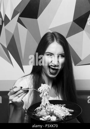 Beautiful woman with expressively opened mouth eating fettuccine Stock Photo