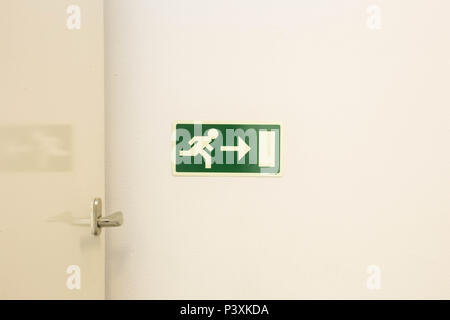 The emergency exit sign shows the direction of escape in case of danger. The emergency exit board hangs on the ceiling of the building. Stock Photo