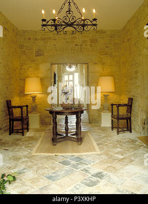 Lighted lamps either side of doorway in French country dining room with oak table and chairs and stone walls Stock Photo