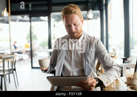 Busy businessman enjoying coffee while online Stock Photo