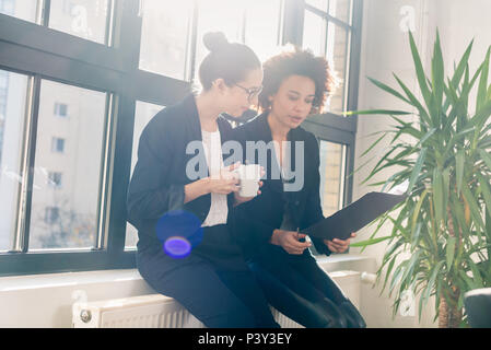 Two young colleagues reviewing business reports during break Stock Photo
