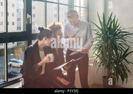 Three young cheerful employees smiling in a modern office Stock Photo
