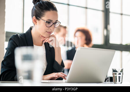 Concentrated business woman reading information on laptop Stock Photo