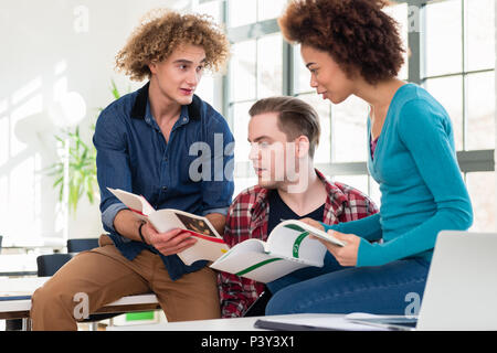Three students comparing information from two different textbooks Stock Photo