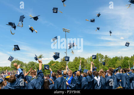 High school graduates throw their caps in the air at the end of a commencement ceremony. Stock Photo