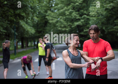 Young sporty couple using smart watches starting their timer before jogging Stock Photo