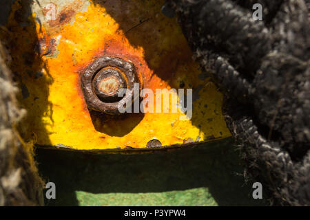 Close-up detail of rusty metal nut and bolt on flat steel plate with peeling yellow paint on the Kamenari-Lepetanecar ferry, Bay of Kotor, Montenegro. Stock Photo