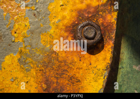 Close-up detail of rusty metal nut and bolt on flat steel plate with peeling yellow paint on the Kamenari-Lepetanecar ferry, Bay of Kotor, Montenegro. Stock Photo