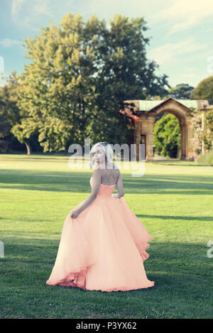blonde woman in peach color tulle ball dress walking in formal garden Stock  Photo - Alamy
