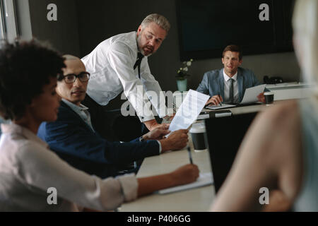 Multi-ethnic business team sitting at conference table and discussing new project. Senior executives working with young managers at office staff meeti Stock Photo