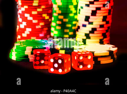 Poker Chips with Red Dice in forground close up on black backgrund, color fantasy, Vegas style Stock Photo