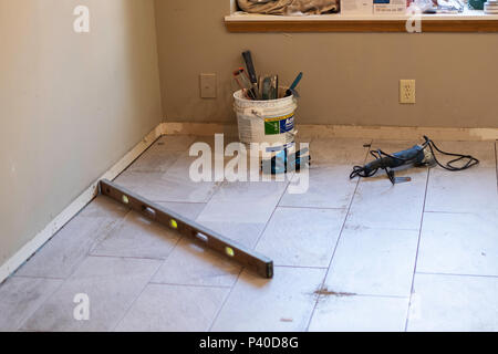 The tools, including a level, of a floor tiler lying on a newly installed ceramic tile floor in Wichita, Kansas, USA. Stock Photo