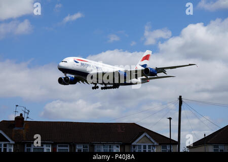 A British Airways Airbus A380-841 aircraft, registration number G-XLED, flying low over houses as it descends for a landing at Heathrow airport. Stock Photo