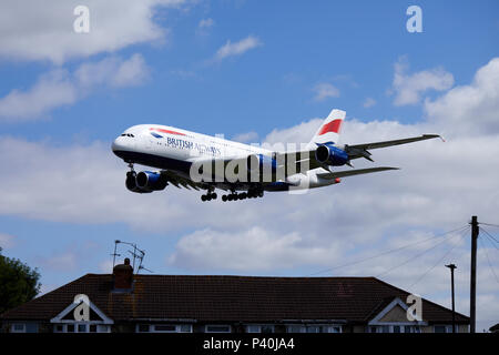 A British Airways Airbus A380-841 aircraft, registration number G-XLED, flying low over houses as it descends for a landing at Heathrow airport. Stock Photo