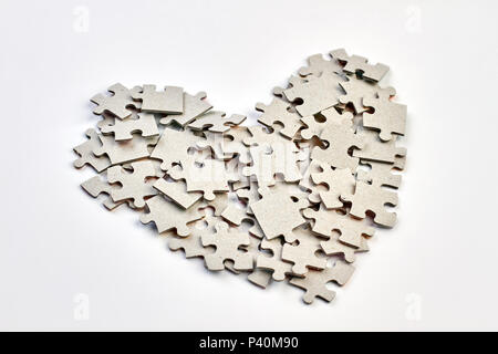 Shape of heart made from cardboard puzzles. Valentines Day background with heart from jigsaw puzzle parts on white background. Stock Photo