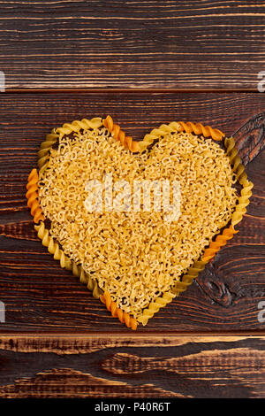 Heart shape from pasta. Uncooked pasta in a shape of heart, top view. Food and love. Stock Photo