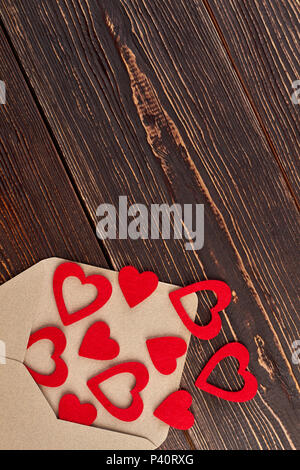 Many red hearts and envelope, top view. Envelope from carft paper and red hearts, copy space. Saint Valentines Day concept. Stock Photo