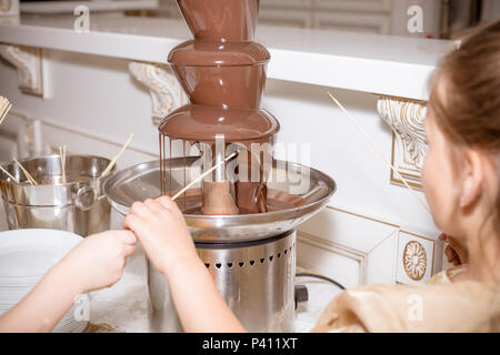 Chocolate fountain with fruits. Chocolate Fountain on children birthday party. Tasty dessert concept.fruit and snack and chocolate fountain. fresh ripe strawberry with chocolate Stock Photo