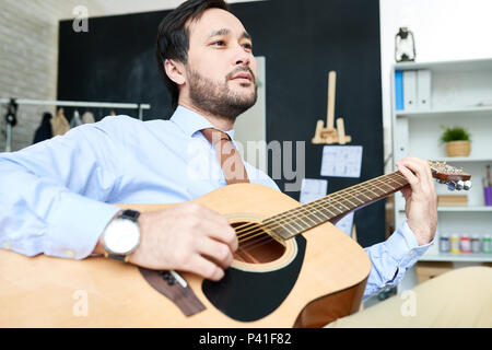 Handsome man with guitar in studio Stock Photo