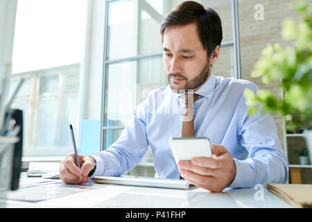 Employee working with smartphone in office Stock Photo