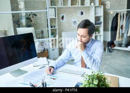 Thoughtful man working in office Stock Photo