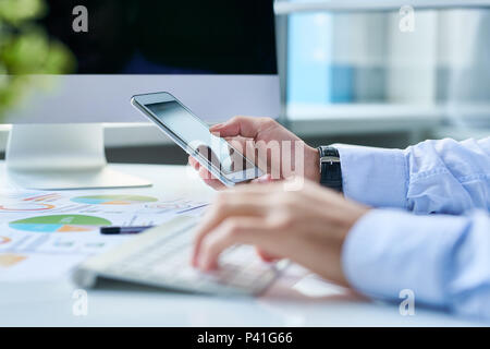 Crop entrepreneur with smartphone at workplace Stock Photo