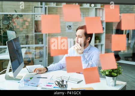 Man working in office behind glass Stock Photo