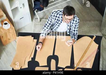 Tailor with phone making clothes patterns Stock Photo